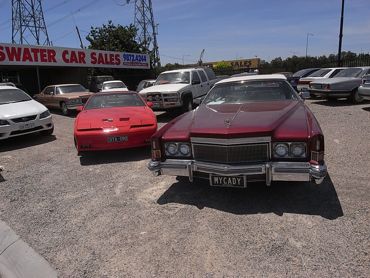 Maroon Cadillac Eldorado convertible and a red Pontiac Firebird