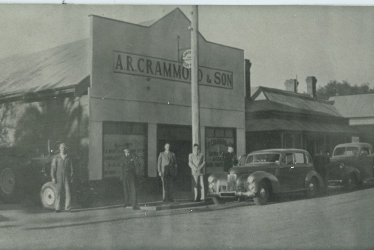 Close view of the A.R. Crammond and Son shopfront with staff and vehicles of the era
