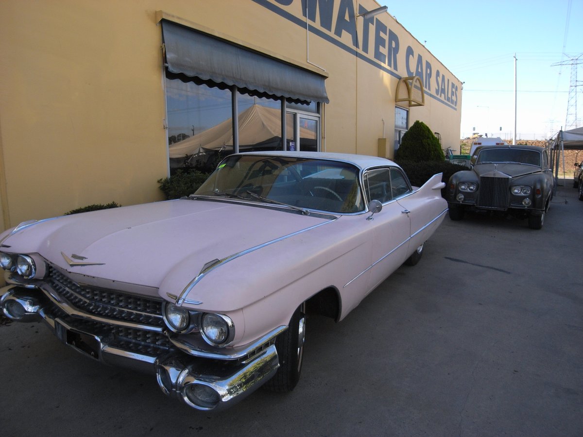 A 1959 Cadillac and a Rolls-Royce Silver Shadow parked outside the Bayswater Car Sales building